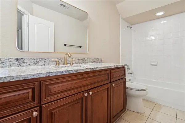 a bathroom with a granite countertop toilet sink and mirror