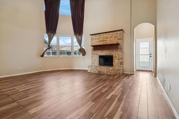 an empty room with wooden floor a fireplace and windows