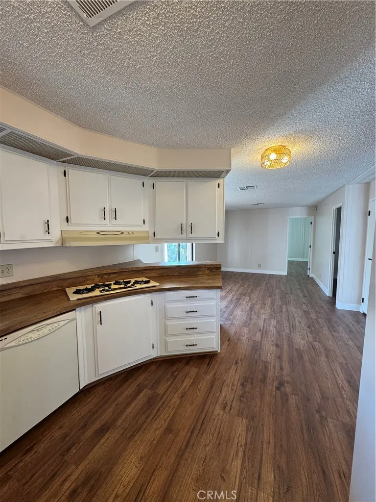 8651 Foothill, Unit 157 Rancho Cucamonga, CA 91730 - Photo 7 of 19 a kitchen with wooden floors and white cabinets