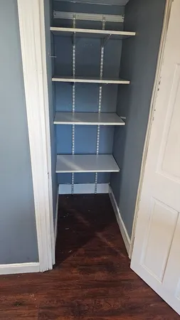 a view of bedroom with wooden floor and shelf