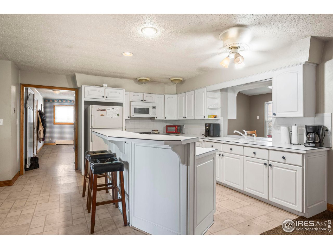 32864 County Road 49 Greeley, CO 80631 - Photo 10 of 40 a kitchen with kitchen island white cabinets and refrigerator