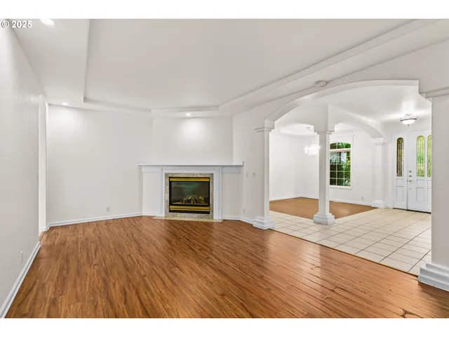 a view of an empty room with window and wooden floor
