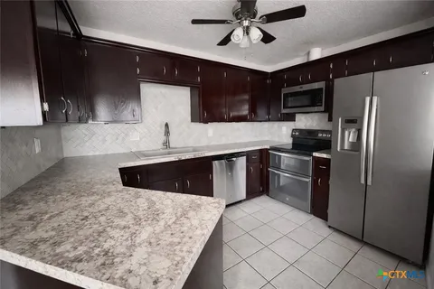 a kitchen with stainless steel appliances granite countertop a sink a stove and a refrigerator