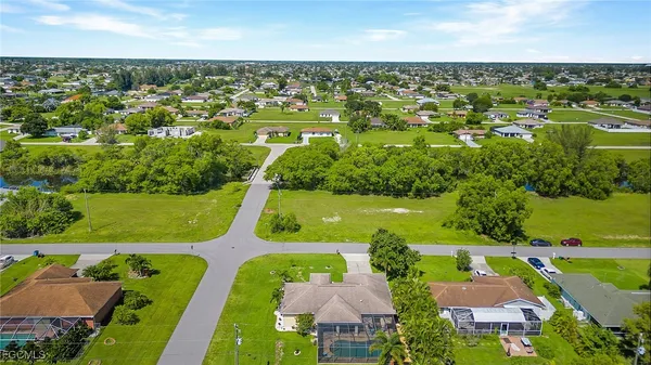 an aerial view of a houses with a garden and lake view