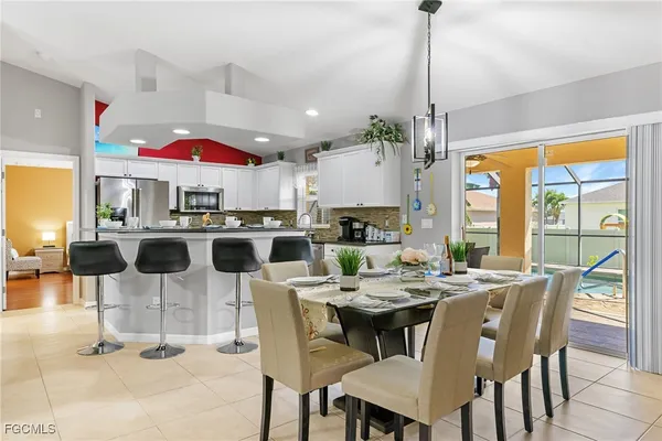 a dining room with stainless steel appliances kitchen island granite countertop lots of white furniture a dining table and chairs