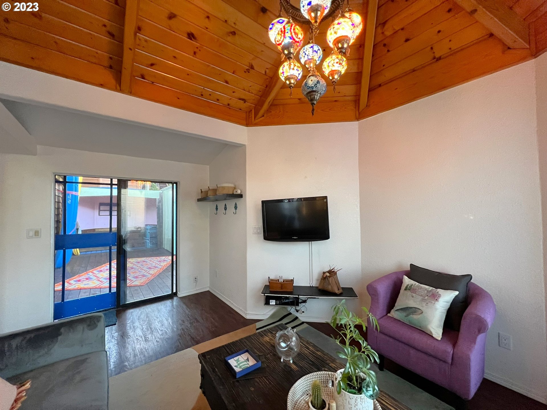 97748 North Bank Chetco River Road, Unit 15 Brookings, OR 97415 - Photo 23 of 48 a living room with furniture a flat screen tv and a floor to ceiling window