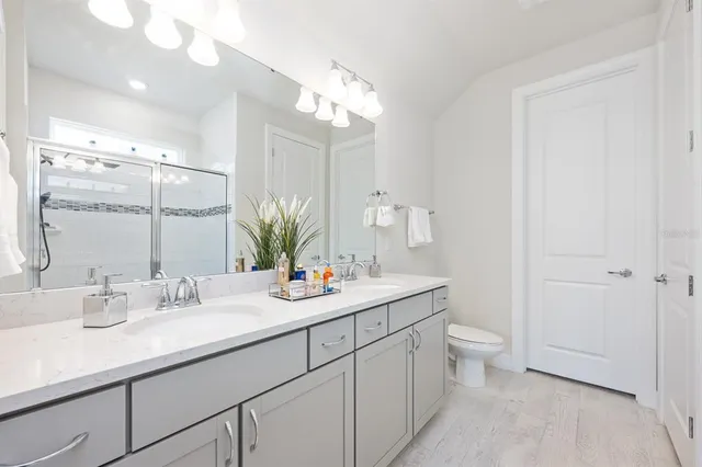 a bathroom with a double vanity sink mirror and shower