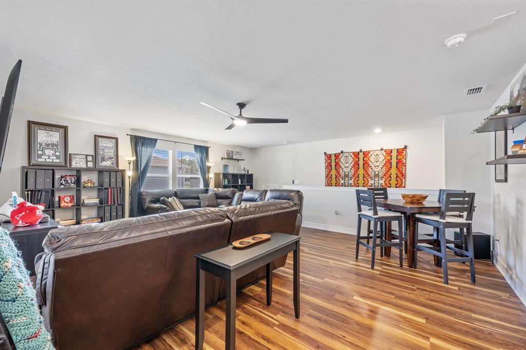 2713 Hilltop Loop Apopka, FL 32712 - Photo 42 of 54 a living room with furniture a dining table and a bookshelf with wooden floor