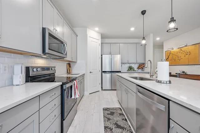 a kitchen with stainless steel appliances granite countertop a refrigerator sink stove microwave and cabinets