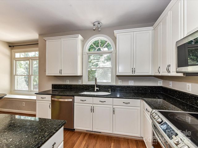 a kitchen with granite countertop a stove a sink and a window