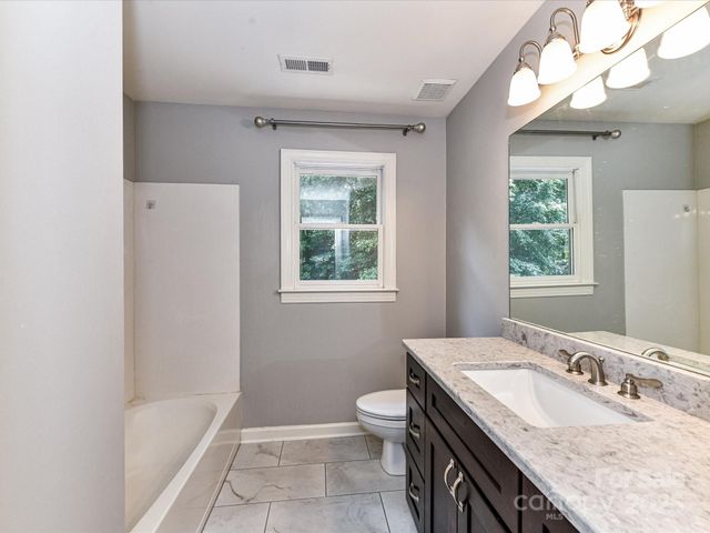 a bathroom with a granite countertop sink a toilet and bathtub