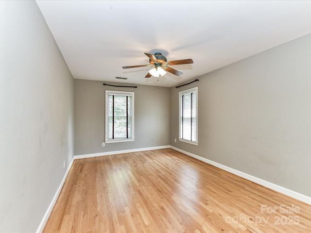 a view of an empty room with chandelier fan and a window