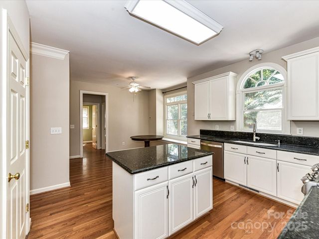 a kitchen with granite countertop a sink and cabinets with wooden floor