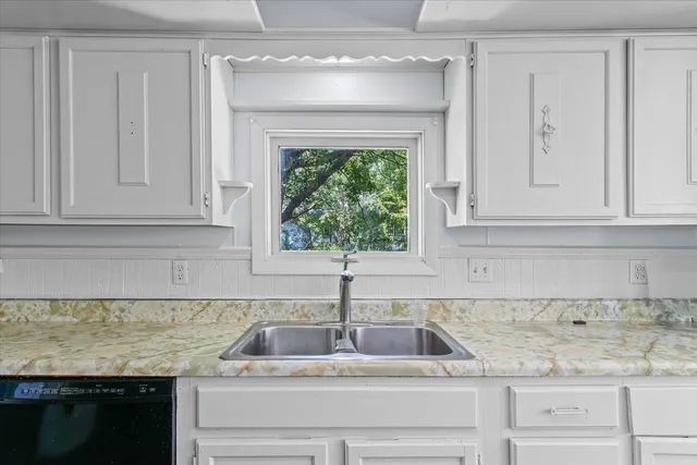 a kitchen with granite countertop white cabinets and a sink