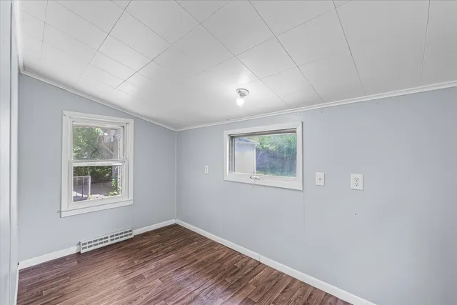 a view of an empty room with a window and wooden floor