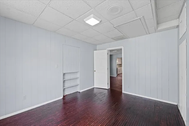a view of an empty room with wooden floor and closet