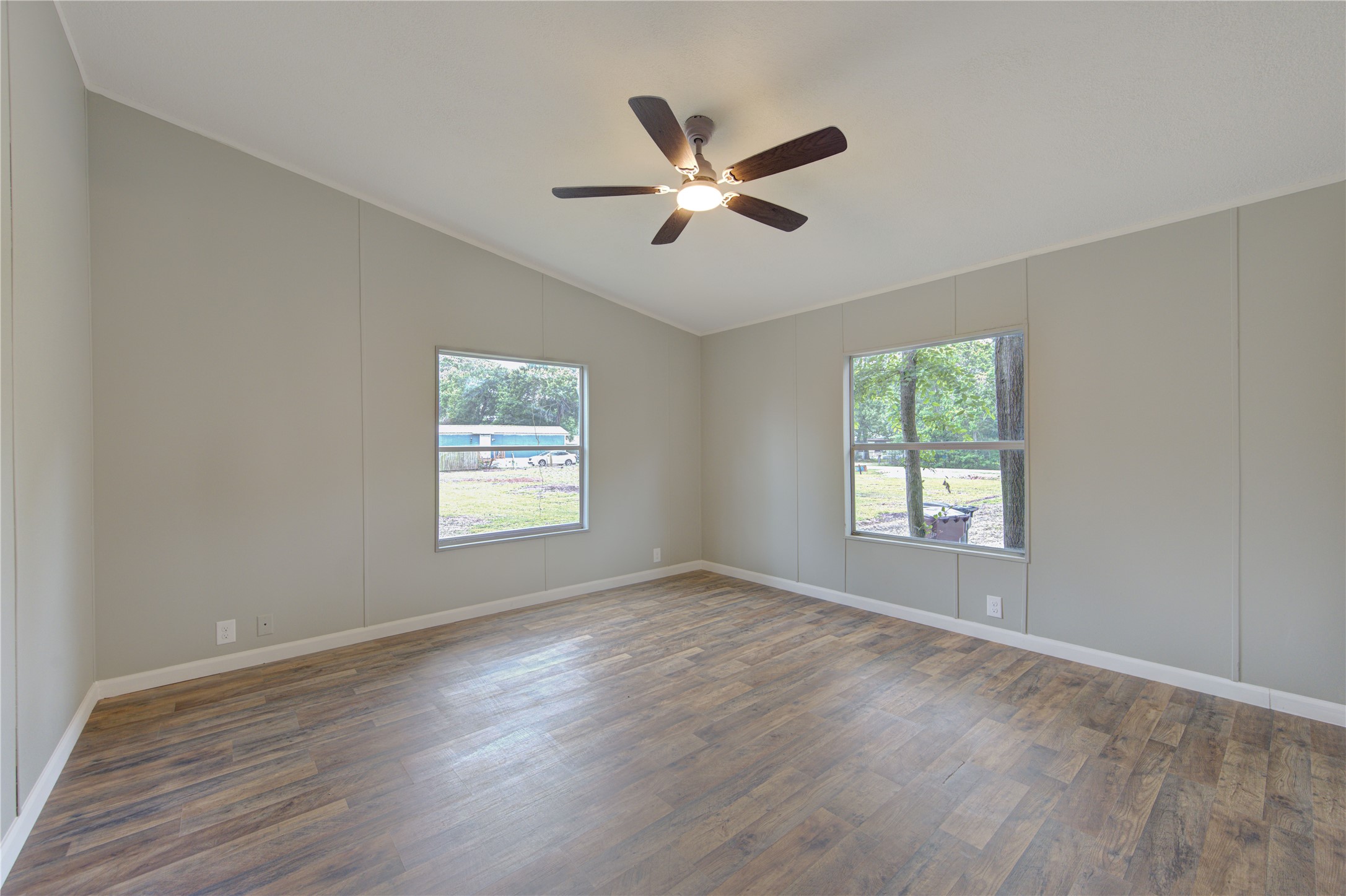 30226 Davis Street Magnolia, TX 77355 - Photo 35 of 50 This room features a spacious interior with light gray walls, wood-look flooring, and a vaulted ceiling with a modern ceiling fan. Large windows provide ample natural light and offer a view of the outdoors.