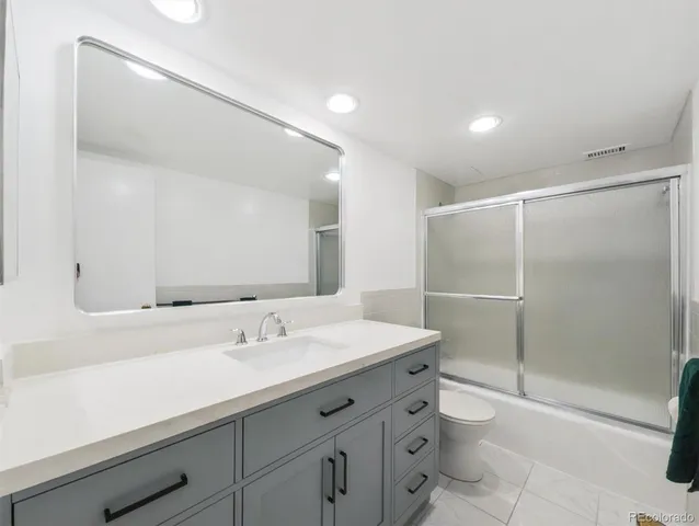a bathroom with a shower sink vanity mirror and toilet