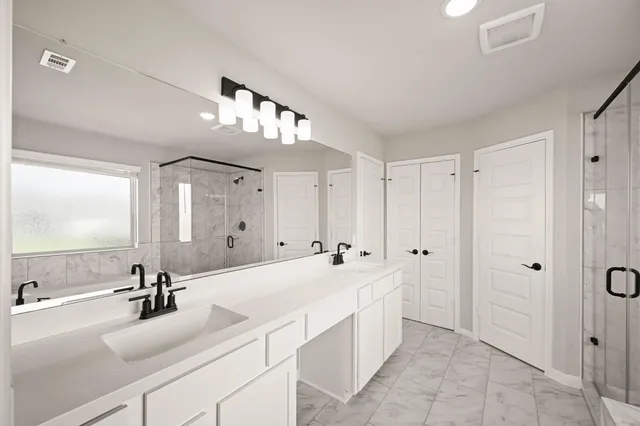 a spacious bathroom with a double vanity sink a mirror and shower