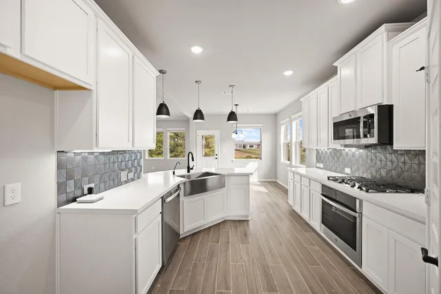 a large white kitchen with stainless steel appliances granite countertop a lot of counter space and wooden floor