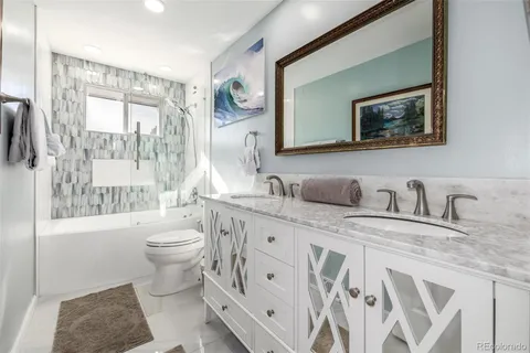 a spacious bathroom with a granite countertop toilet a sink and a large mirror