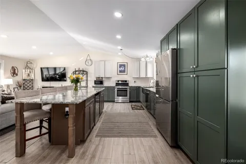 a kitchen with stainless steel appliances granite countertop a refrigerator a stove and a sink