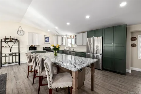 a kitchen with kitchen island a dining table chairs and refrigerator