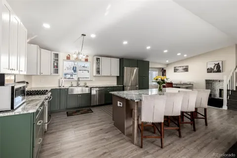 a kitchen with stainless steel appliances kitchen island granite countertop a table chairs sink and cabinets