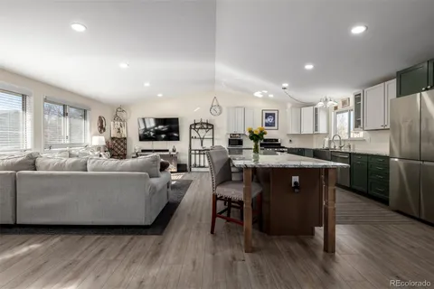 a living room with stainless steel appliances kitchen island granite countertop wooden floor a dining table and chairs