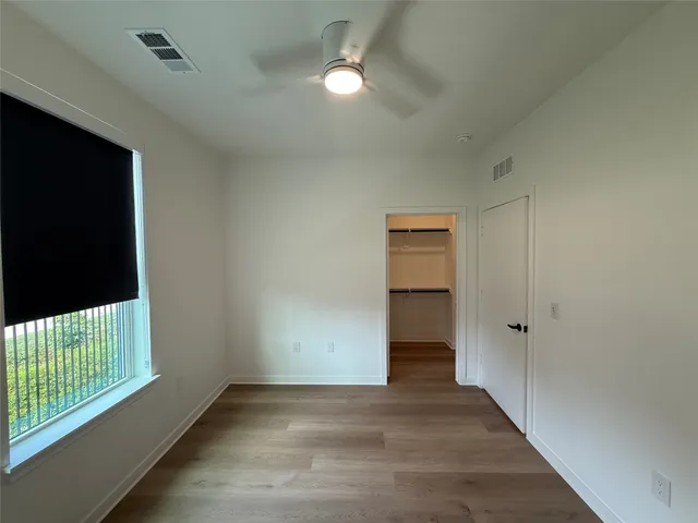 an empty room with wooden floor and a ceiling fan