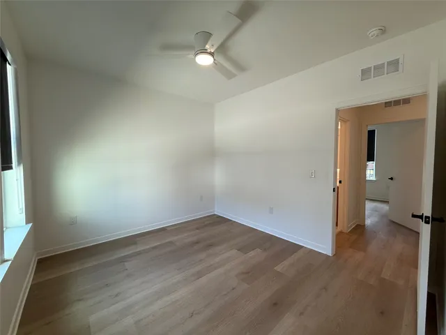 an empty room with wooden floor and a ceiling fan