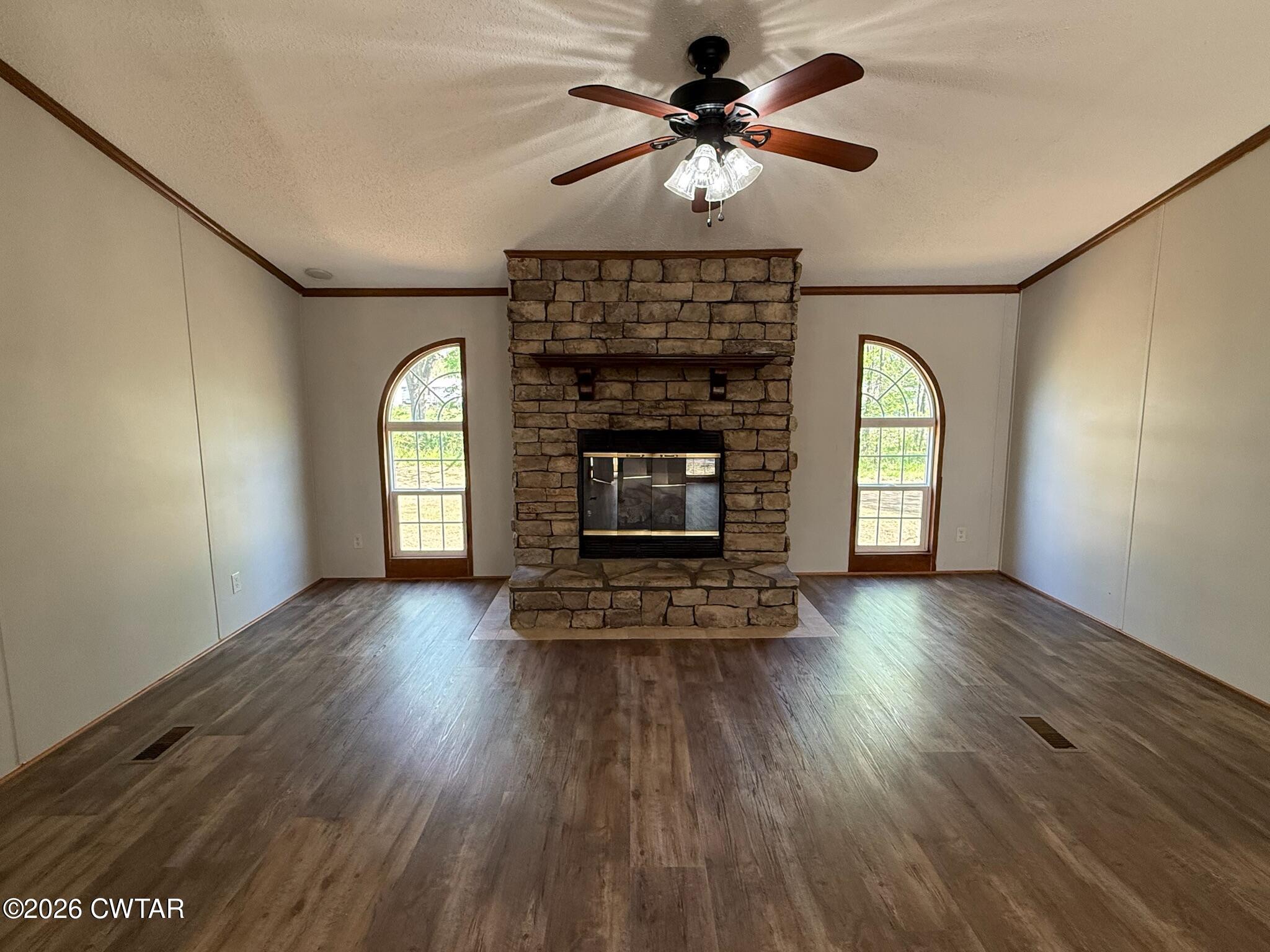 226 Massey Street Adamsville, TN 38310 - Photo 5 of 28 an empty room with windows fireplace and wooden floor