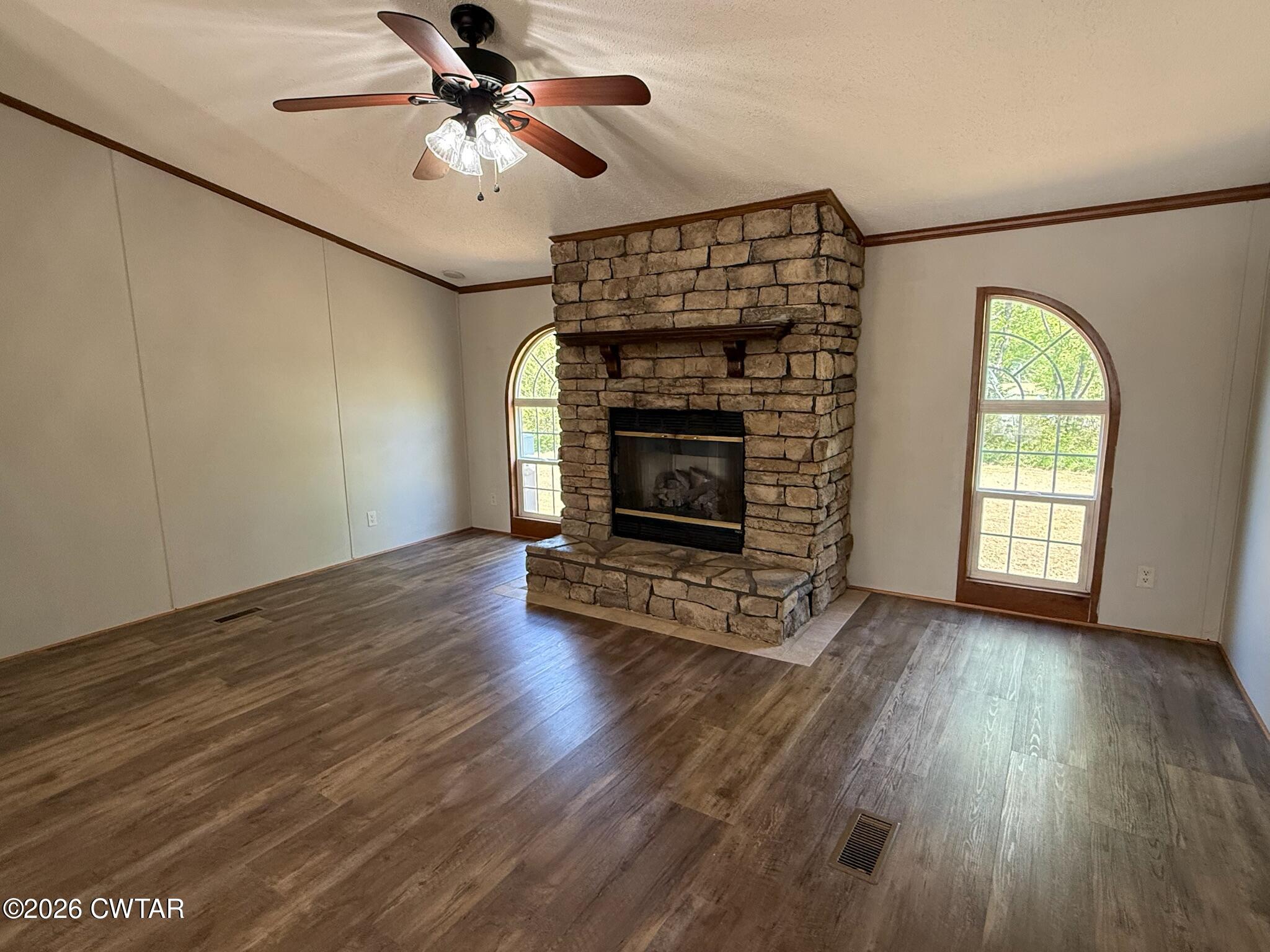 226 Massey Street Adamsville, TN 38310 - Photo 6 of 28 an empty room with wooden floor fireplace and windows