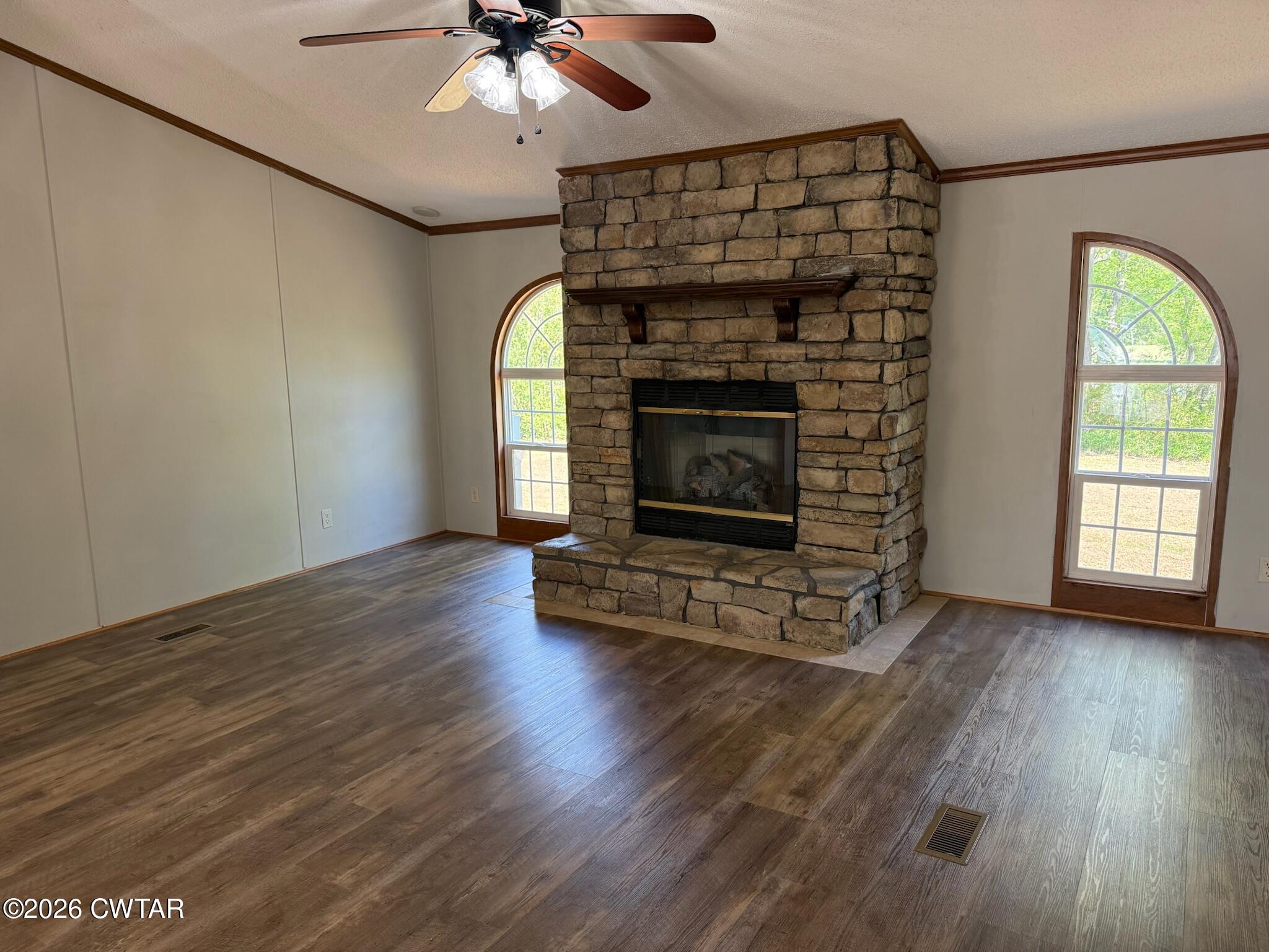 226 Massey Street Adamsville, TN 38310 - Photo 7 of 28 an empty room with wooden floor fireplace and windows