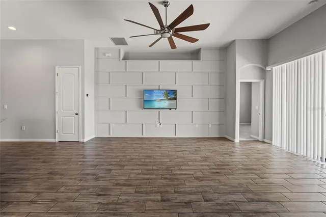 a view of a livingroom with a chandelier fan and wooden floor