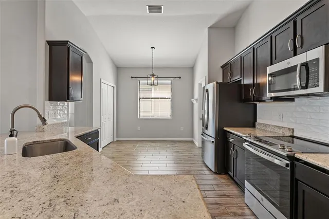a kitchen with stainless steel appliances granite countertop a sink stove and refrigerator
