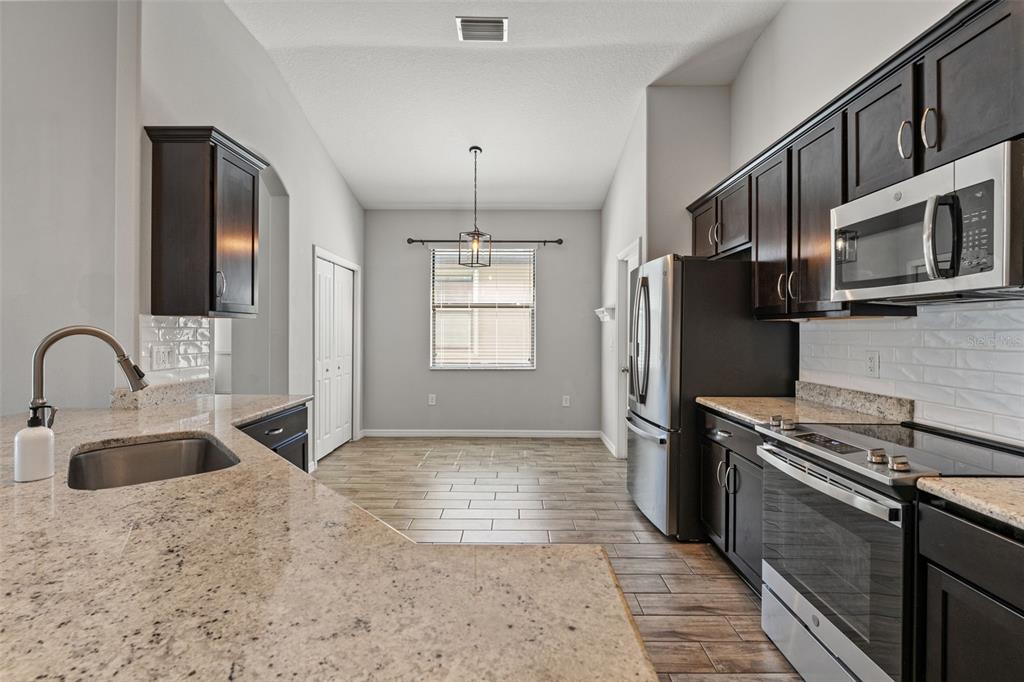 335 Old Windsor Way Spring Hill, FL 34609 - Photo 6 of 41 a kitchen with stainless steel appliances granite countertop a sink stove and refrigerator