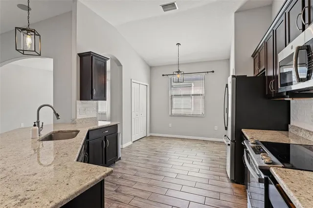 a kitchen with stainless steel appliances granite countertop a sink a stove and refrigerator