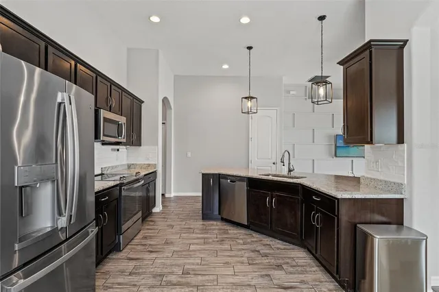 a large kitchen with stainless steel appliances a sink and a refrigerator
