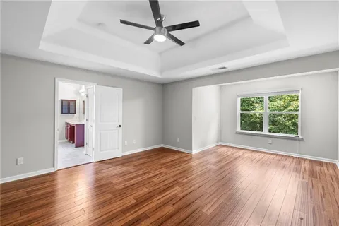 a view of an empty room with window and wooden floor