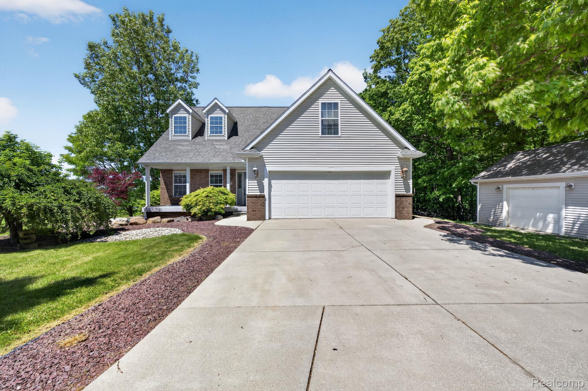 9055 Hegel Road Grand Blanc, MI 48439 - Photo 1 of 62 Traditional-style home featuring light gray siding, a covered front porch, and a two-car attached garage