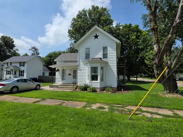 a front view of a house with a yard and trees