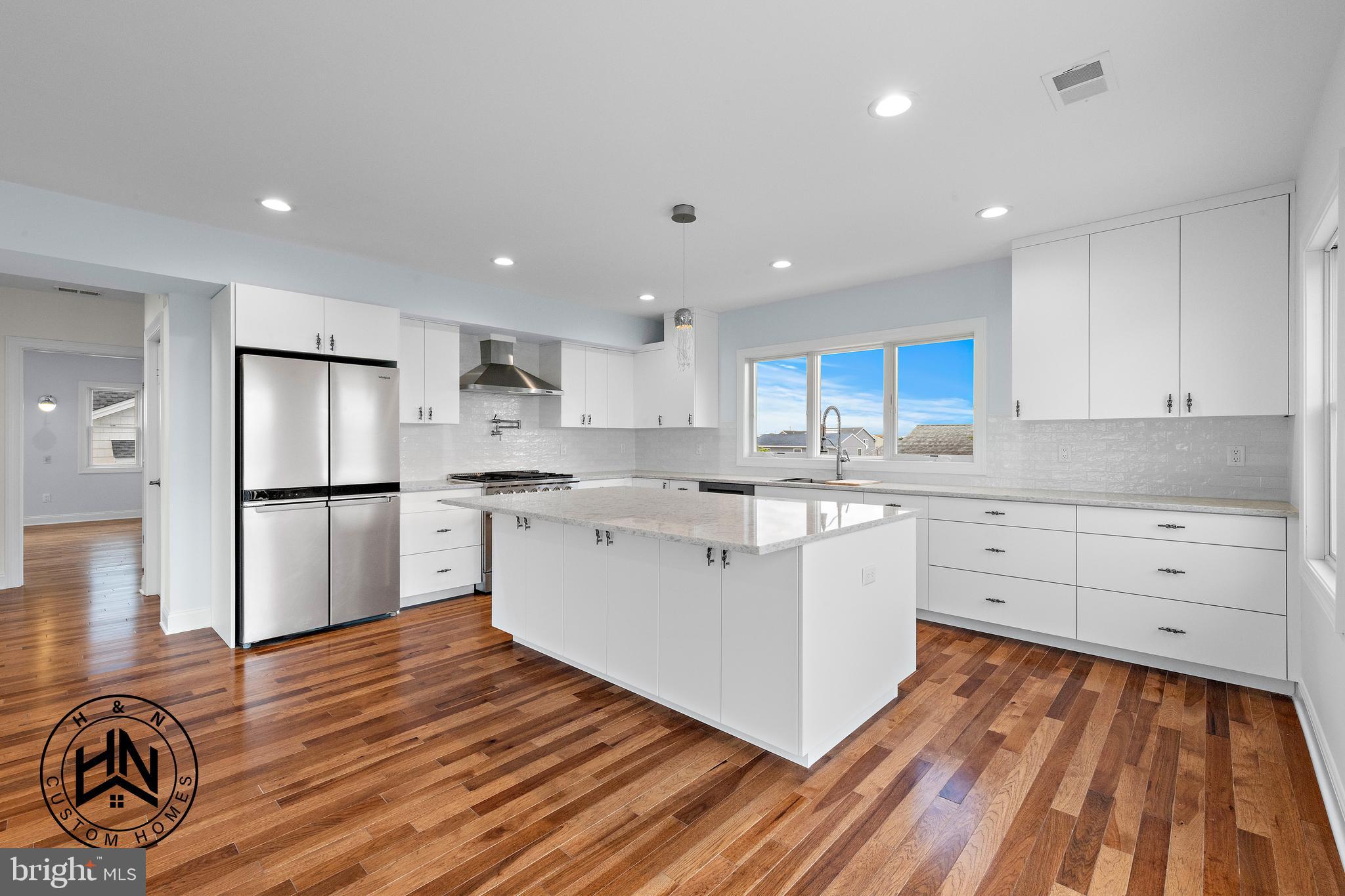 24 West 53rd Street Long Beach Township, NJ 08008 - Photo 24 of 75 a kitchen with white cabinets wooden floor and stainless steel appliances
