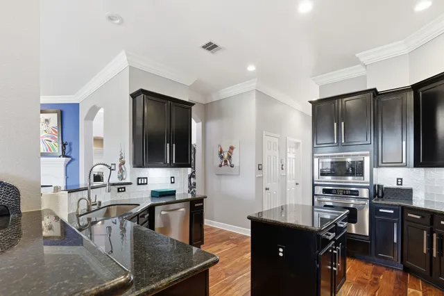 a kitchen with stainless steel appliances granite countertop a stove a sink a refrigerator and a microwave