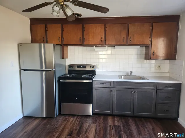 a kitchen with stainless steel appliances granite countertop a refrigerator a sink and wooden cabinets