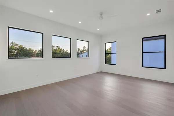 an empty room with wooden floor and windows