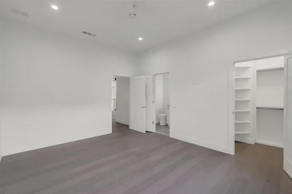 a view of an empty room with wooden floor and closet