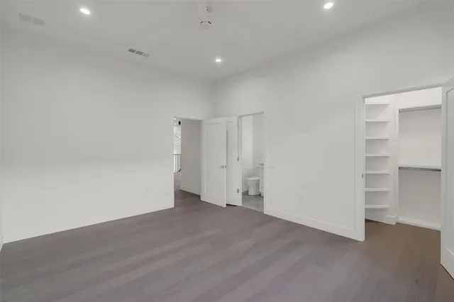a view of an empty room with wooden floor and closet