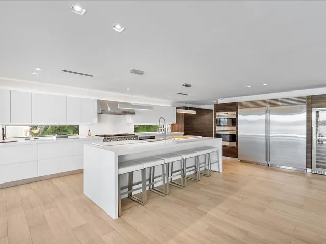 a kitchen with kitchen island a stove a sink a refrigerator and white cabinets with wooden floor