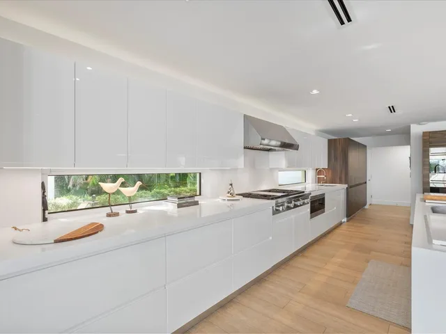 a large white kitchen with stainless steel appliances granite countertop a stove and a sink